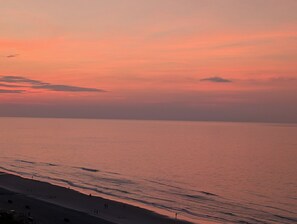 Een strand met een rustige zee en een zonsondergang.