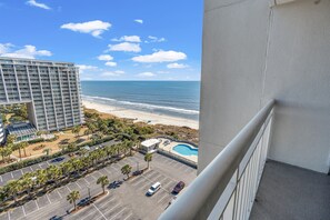 Hotel met zwembad, uitzicht op het strand en parkeerplaats.