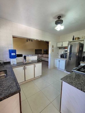 A kitchen with a refrigerator, stove, and a water dispenser.