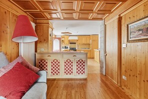 A cozy room with a wooden ceiling, a kitchenette, and a dining area.