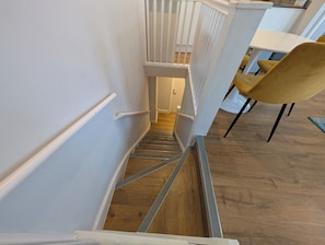 Eine Treppe mit Handlauf, Holzboden und weißer Wand.