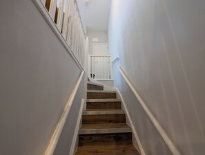Eine Treppe mit Holzdielen und weißen Geländern, die zu einer Tür führt.
