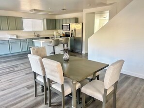 A modern kitchen with a dining area, featuring a stainless steel refrigerator, a built-in oven, and a bar island with seating. - Prime North Scottsdale Retreat Near Golf, Hiking, Shops, Dining & Loop 101 (Scottsdale)