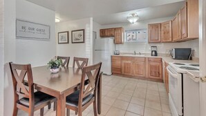 Una cocina moderna con armarios de madera, una mesa de comedor con sillas y un refrigerador.