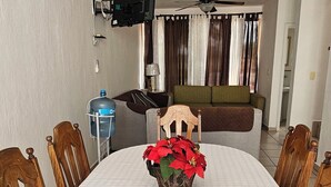 A dining area with a round table, chairs, a television mounted on the wall, and a ceiling fan. - Casa Bonita in Nuevo Vallarta: Enjoy Your Beach Vacation (Mezcales)