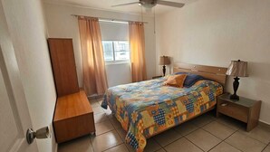 A bedroom with a bed, bedside tables, a ceiling fan, and a window with curtains. - Casa Bonita in Nuevo Vallarta: Enjoy Your Beach Vacation (Mezcales)