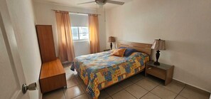 A bedroom with a bed, bedside tables, a ceiling fan, and a window with curtains. - Casa Bonita in Nuevo Vallarta: Enjoy Your Beach Vacation (Mezcales)