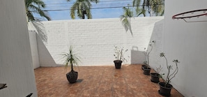 A courtyard with a white brick wall, potted plants, and a tiled floor. - Casa Bonita in Nuevo Vallarta: Enjoy Your Beach Vacation (Mezcales)