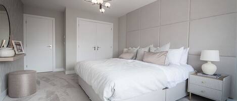 Un dormitorio con una cama grande, una mesita de noche con lámpara y una lámpara colgante.