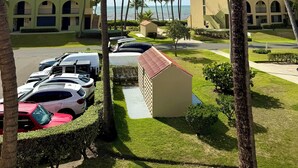 A hotel with multiple-story buildings, a parking area with cars, and palm trees. - Family Retreat @Palm 5 Golf View (Palmas del Mar)