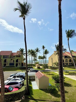 Ein Hotel mit mehrstöckigen Gebäuden, einem Parkplatz mit Autos und Palmen.