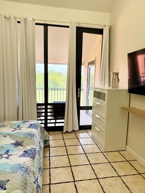 A bedroom with a bed, a television, a wardrobe, and a sliding glass door leading to a balcony. - 2-Story Beachfront Penthouse Steps to the Sand (Palmas del Mar)