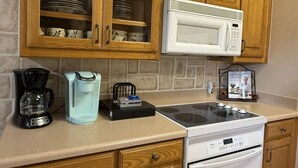 A kitchen with wooden cabinets, a microwave, a coffee maker, and a stove. - Oasis at Eagle Mountain Lake (Azle)