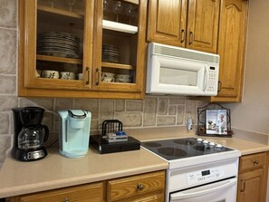 A kitchen with wooden cabinets, a microwave, a coffee maker, and a stove. - Oasis at Eagle Mountain Lake (Azle)