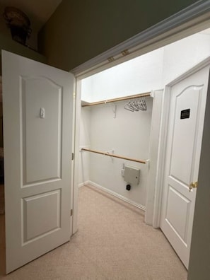 Ein Flur mit weißen Türen, einer Holzkleiderstange und einem Lichtschalter an der Wand.