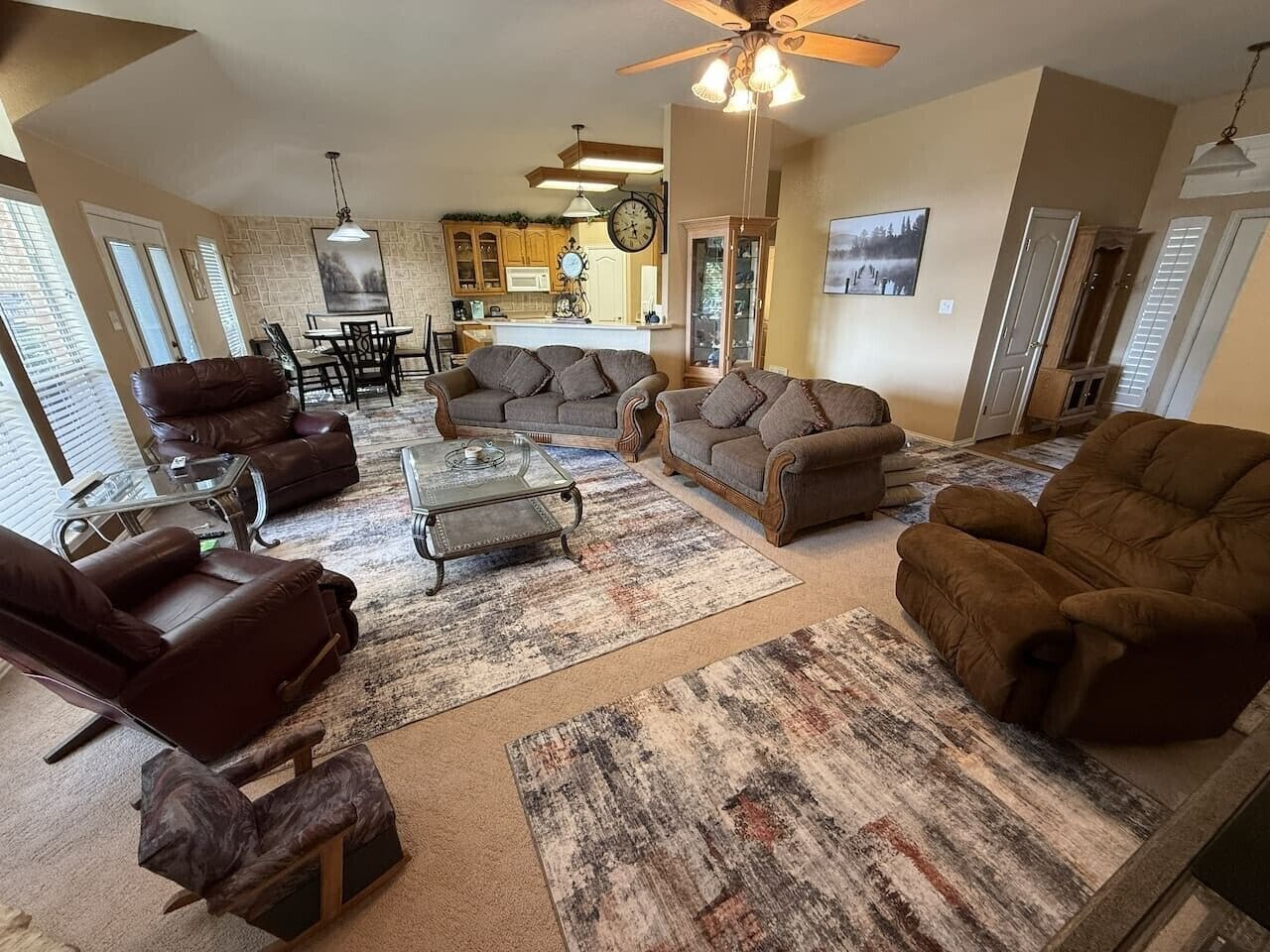 A spacious living room with a fireplace, leather sofas, a coffee table, and a dining area with a chandelier.