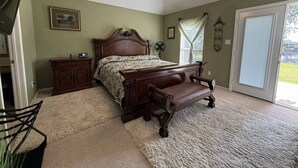 A bedroom with a bed, a nightstand, a chair, a ceiling fan, and a window with curtains. - Oasis at Eagle Mountain Lake (Azle)