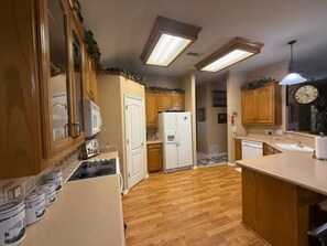 Une cuisine avec des meubles de rangement en bois, un réfrigérateur blanc et un plan de travail doté d’un évier.