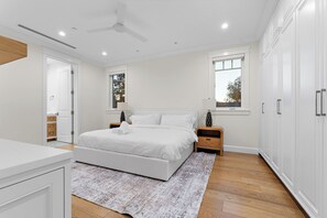 Ein Schlafzimmer mit einem Bett, Nachttischen, einem Fenster und einem Deckenventilator.