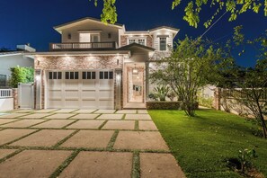 Ein zweigeschossiges Haus mit Garage, gepflegtem Rasen und Ziegelaußenwand.