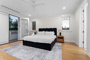 Een moderne slaapkamer met een groot bed, een plafondventilator en uitzicht op de omgeving door een deur.
