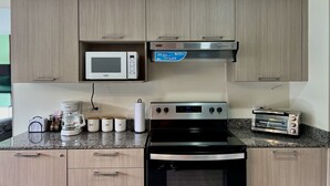 Una cucina dotata di microonde, tostapane, fornello e pensili.