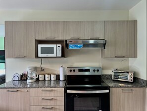 A kitchen with a microwave, toaster, stove, and cabinets. - Modern 1-bedroom apartment in wonderful San Salvador with Pool & Gym (San Salvador)