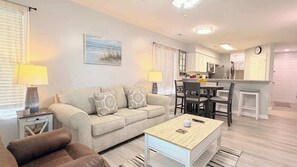 Een woonkamer met een bank, een salontafel en een eethoek met stoelen en een tafel.