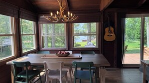 Een eethoek met een tafel en stoelen, een kroonluchter en een gitaar aan de muur.