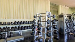 Ein Fitnessstudio mit Kraftgeräten, darunter Kurzhanteln und einem Hantelständer.