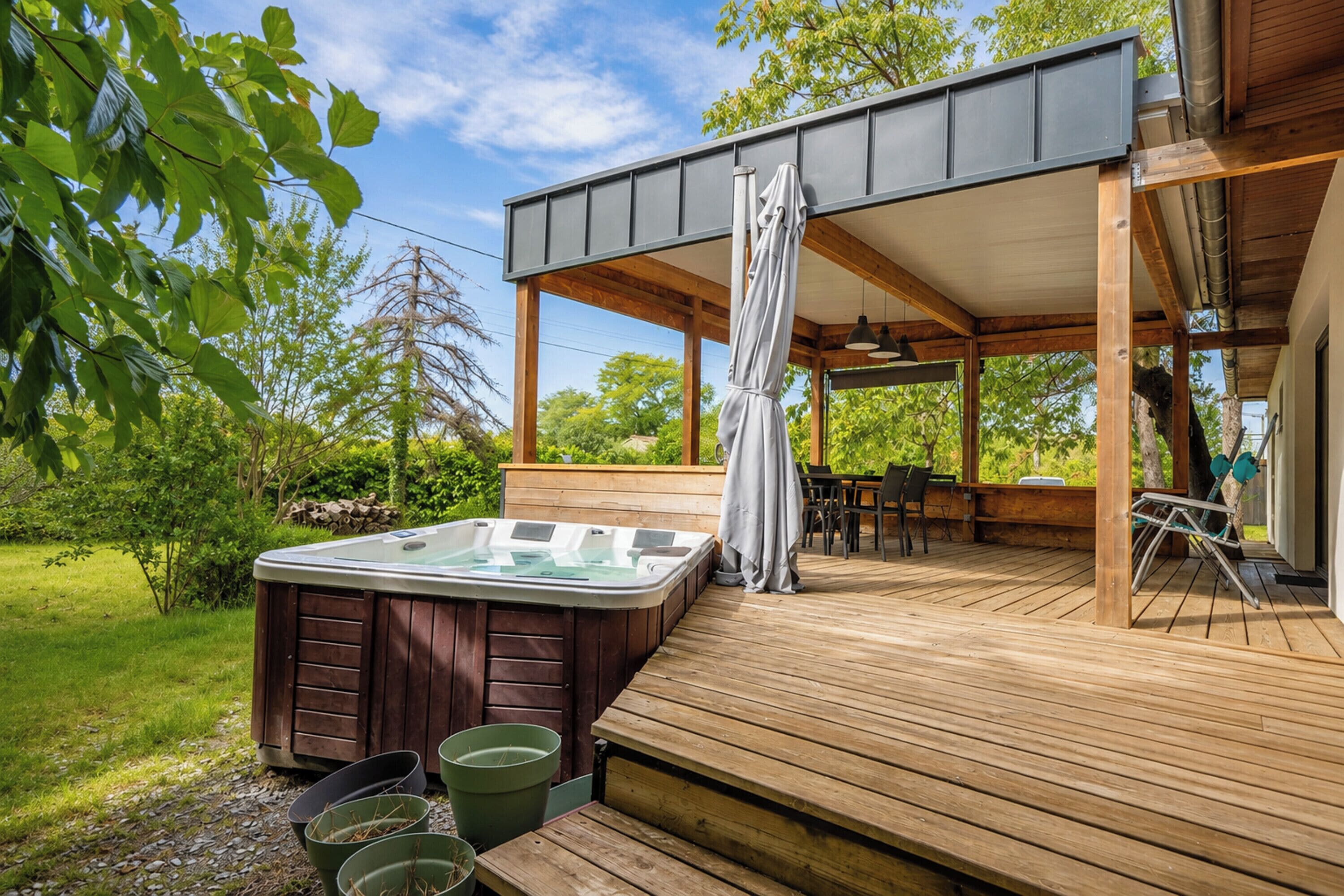 A wooden deck with a hot tub, outdoor seating, and a covered area.