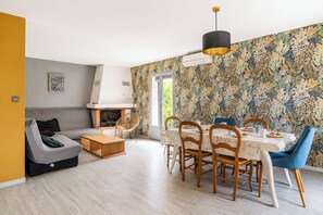 Ein modernes Wohnzimmer mit einer Couch, einem Esstisch mit Stühlen, einem Kamin und einer Wand mit Muster.