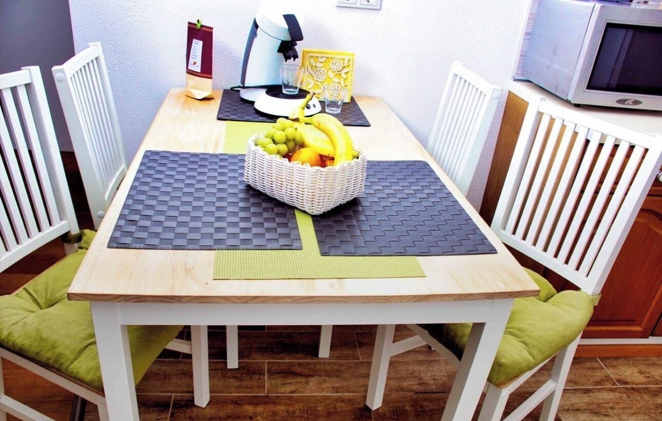 A dining table with a basket of fruit, a coffee machine, and a microwave.