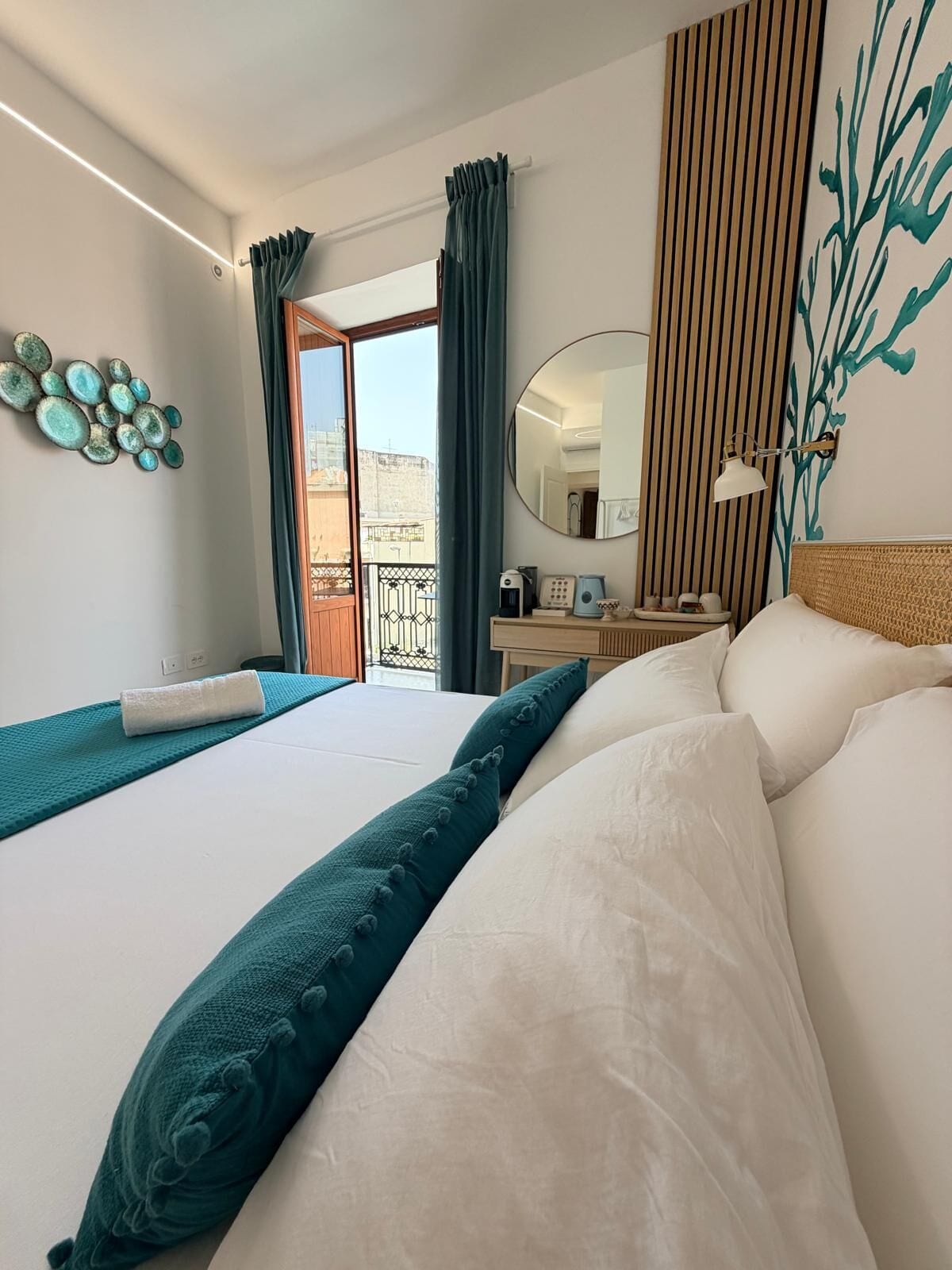 A hotel room with two beds, a large window, a balcony, and a view of the city.