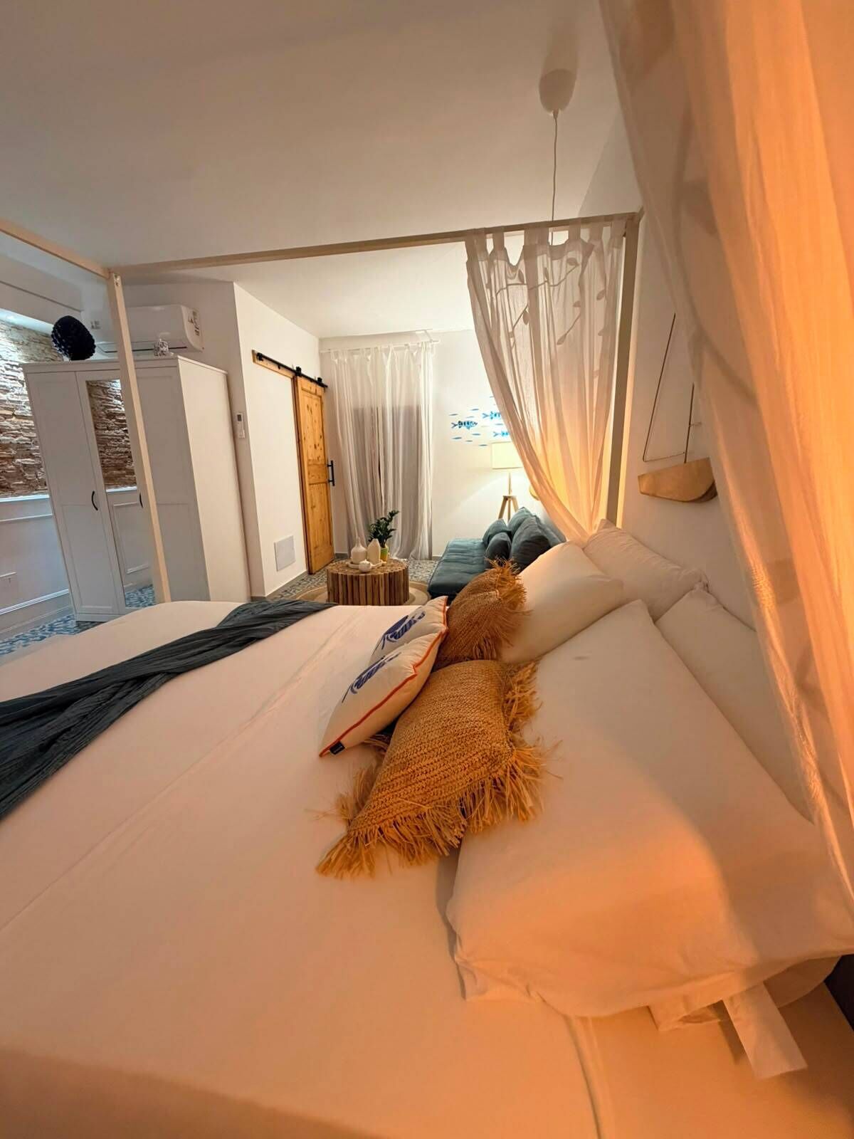 A bedroom with a bed, a wardrobe, a bedside table, and a window with curtains.