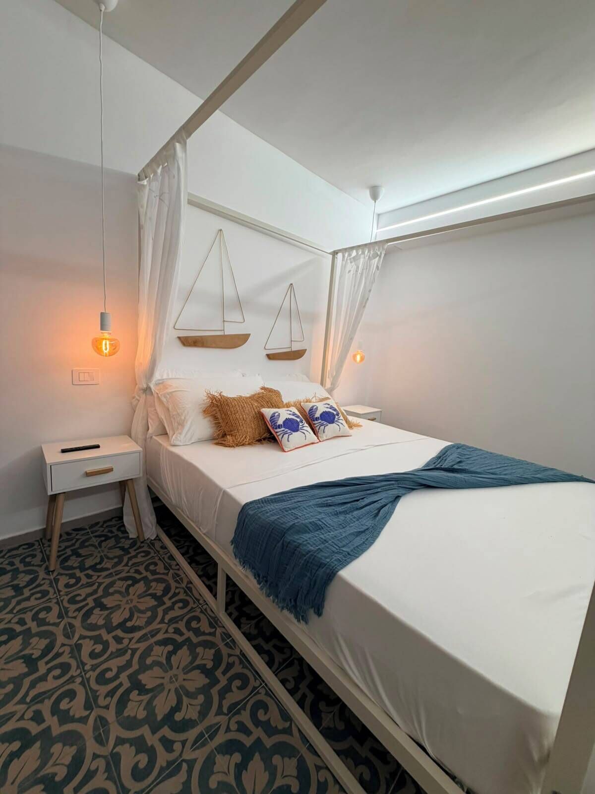 Una cama con dosel, una mesita de noche y un adorno con forma de balanza en la pared.