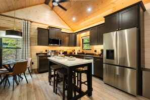 A modern kitchen with dark cabinetry, stainless steel appliances, and a wooden ceiling. - New Cabin - Indoor Swim Spa, Hot Tub, Game Room! (Gatlinburg)