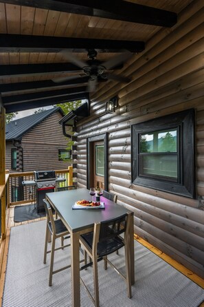 Une cabane en rondins de bois comprenant un coin repas avec une table et des chaises, un barbecue et une vue sur l’extérieur.