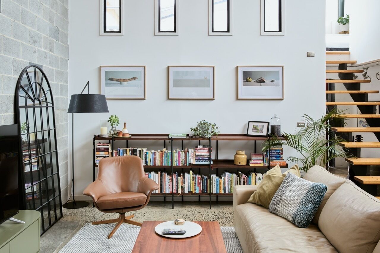 A living room with a bookshelf, a leather armchair, a sofa, and a coffee table.