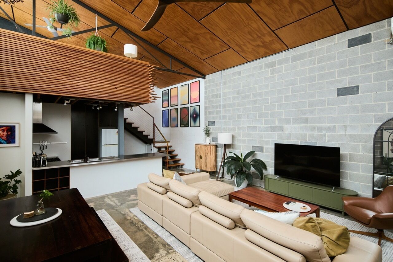 Un salon moderne avec un canapé d’angle, un téléviseur à écran plat et un escalier menant à un niveau supérieur.