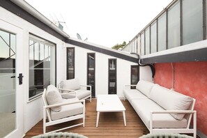 Eine Terrasse mit weißer Möbel, darunter Sofas und ein Tisch, und eine rote Wand.