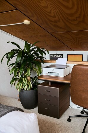Un espacio de trabajo en casa con una impresora, una planta en maceta y una lámpara de escritorio.