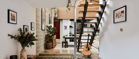 Una scala conduce a un secondo piano, con una chitarra appoggiata al muro.