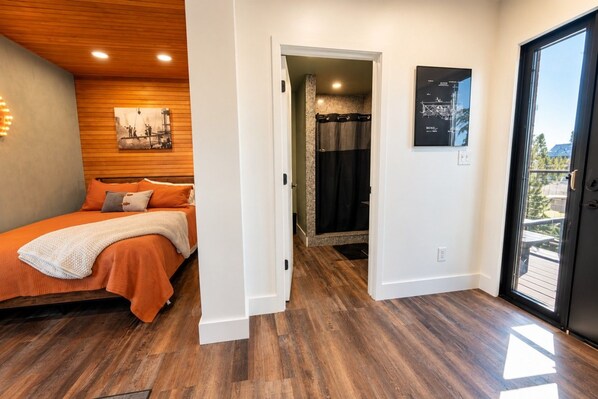 Quarto com cama, chuveiro e porta para uma varanda.