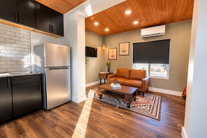 Um espaço de estar compacto com cozinha compacta, sofá e mesa de centro.