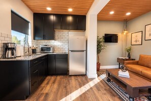 A modern kitchen with black cabinets, a white refrigerator, and a built-in oven. - Modern Cargo House in Salt Lake City (Salt Lake City)