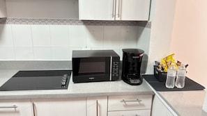 A kitchen with a microwave, coffee maker, and water bottles on the counter. - Casablanca (Santa Ana)