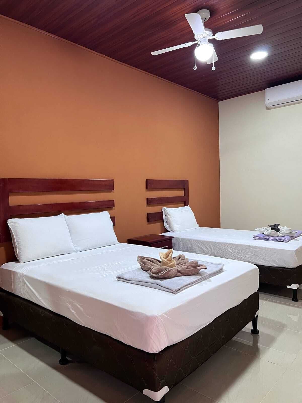 Une chambre d’hôtel avec deux lits, un ventilateur de plafond et une table de chevet.