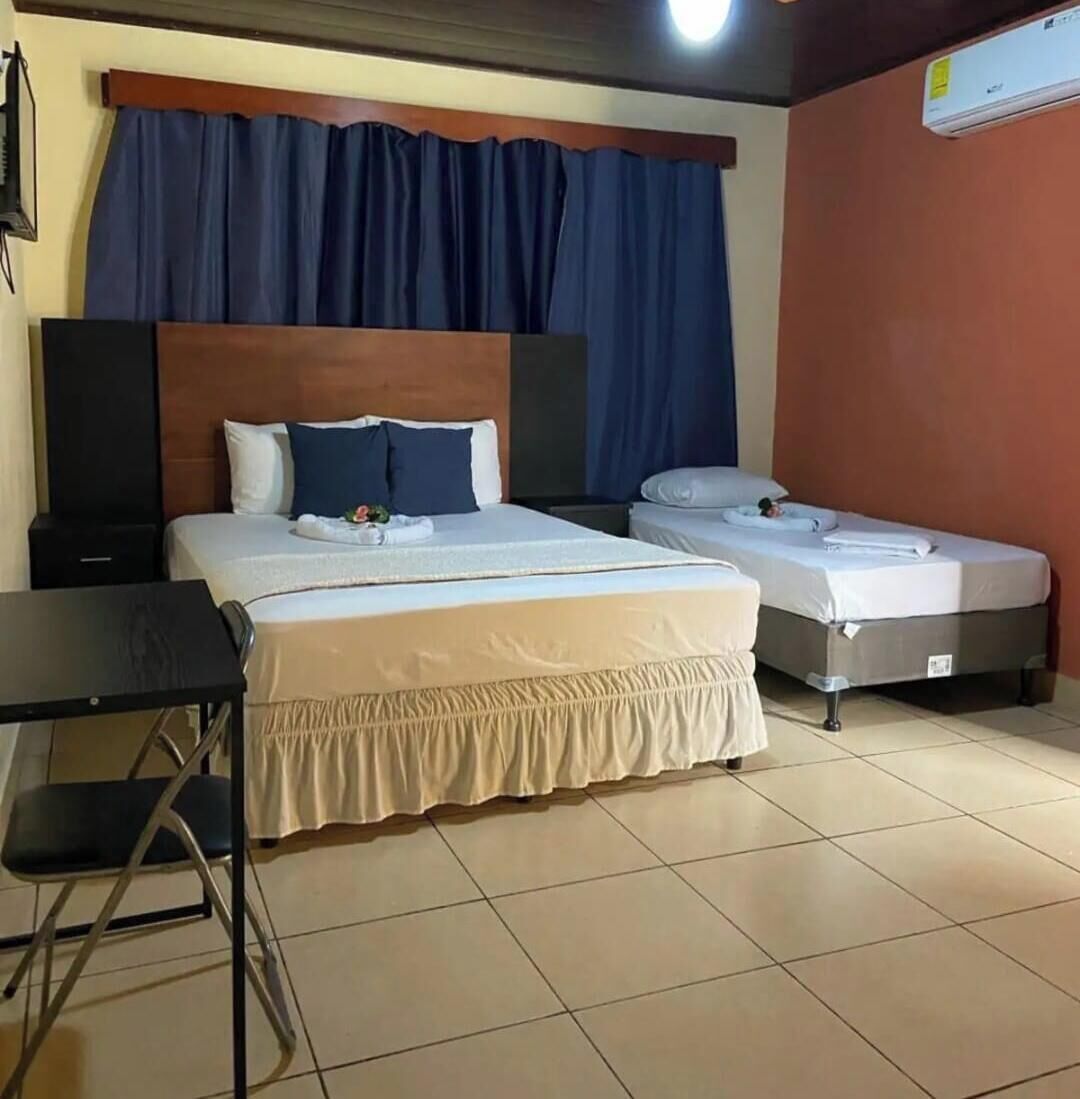 A hotel room with a large bed, a smaller bed, a desk, and a chair.