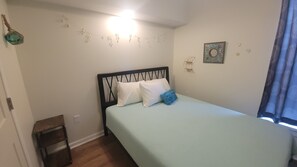 Una camera da letto con un letto, un comodino, una mensola a muro e una finestra con tende.